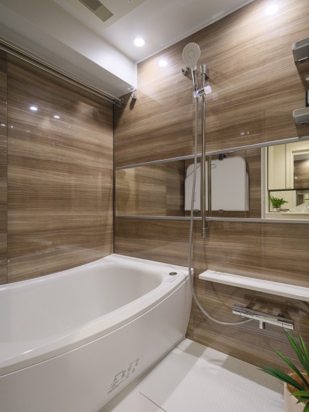 光沢のある木目調パネルが高級感を漂わせるバスルームです。浴槽は美しいカーブと全身を包み込むような入浴感が特長です。