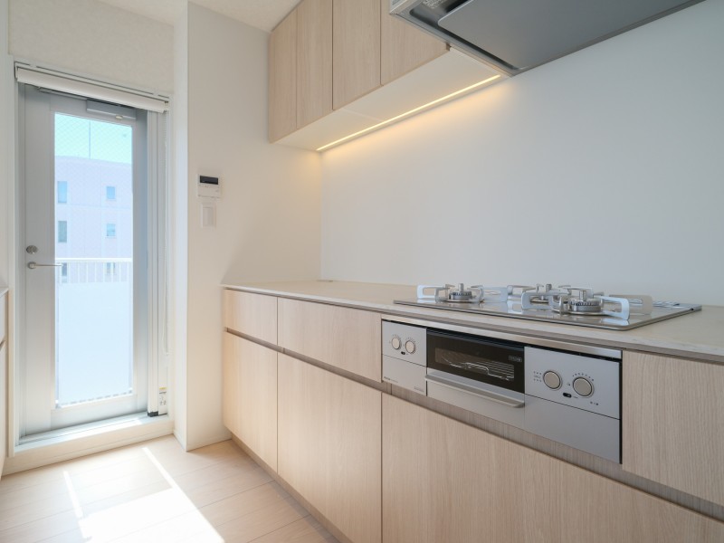 美しい木目の面材はインテリアの一部のようでお部屋の雰囲気に溶け込みます。Ⅱ列型キッチンなので、作業スペースが広くゆとりのある「居心地」も良いスペースです。