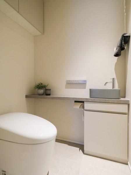 レストルームにはすっきりとしたシルエットのタンクレストイレを採用しています。手洗いカウンターや上部吊戸棚収納を備えた機能的な設計です。