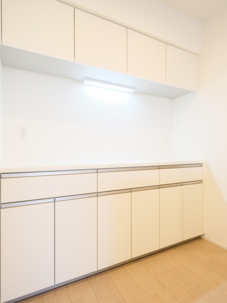 キッチンの背面には、お揃いのデザインのカップボードが設置されております。吊戸棚と足元に収納棚があり、食器や調味料など様々なものを収納することができます。