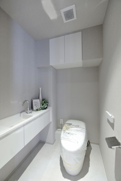 独立した手洗いカウンターを備えたホテルライクなトイレ空間です。吊戸棚やカウンター下収納を設けることで、機能性と美しい空間性を両立しています。日用品の収納にも配慮されています。