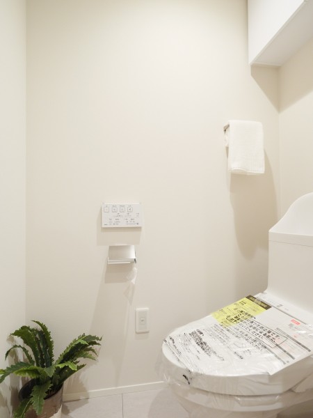 シンプルで安らぎが宿るレストルームです。吊戸棚にはトイレットペーパーや掃除用具を収納でき、生活感を抑えたすっきりとした空間を実現します。