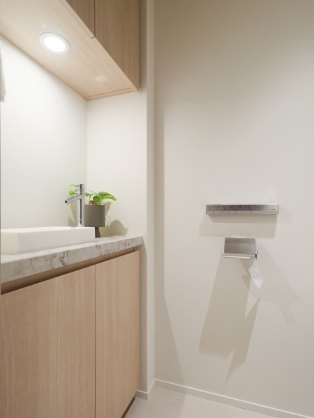 レストルームには手洗いカウンターを備え付けました。吊戸棚やカウンター下収納にはトイレットペーパーや掃除用具を収納でき、生活感を抑えたすっきりとした空間を実現します。