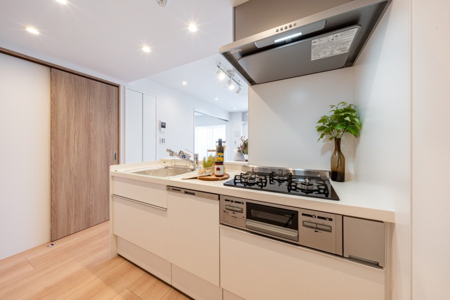 お部屋の色合いに溶け込むソリッドホワイト基調のオープンシステムキッチンです。油跳ねが心配なコンロ前のみ壁付けとし、家事時短に便利な食洗器を搭載しています。