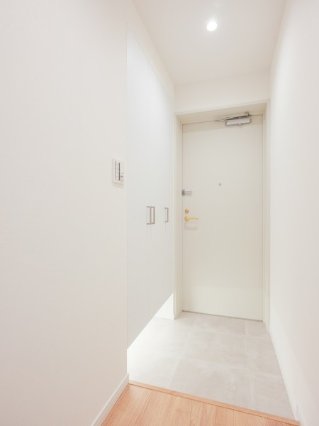 フットライトの光がやさしく足元を照らすホワイトカラーの玄関です。人感センサーライト付きで帰宅時にスイッチを探す必要がなく、明るい空間がお迎えします。