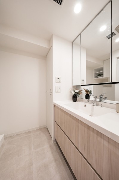 空間に美しく溶け込むスタイリッシュなデザインの洗面化粧台は、大きな三面鏡で身だしなみも整えやすく、収納豊富で実用的な洗面空間です。タオルや小物の収納に便利なリネン庫も備え付けています。