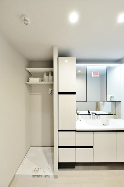 三面鏡裏の収納に、キャビネットを備え付け大容量の収納ですっきりとした空間を保てる洗面室です。洗濯機置き場の上にも収納棚を設置し、細部の収納量にまで目を向けました。