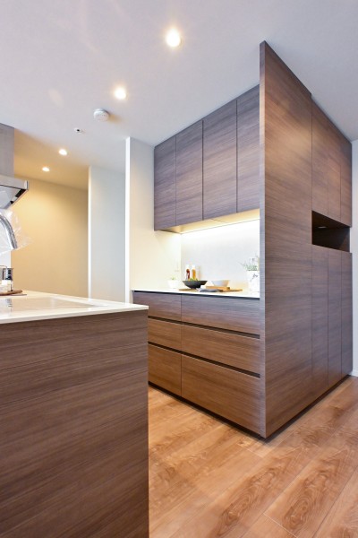 キッチン背面には収納豊富でカウンタースペースも広いカップボードがあります。間接照明が優しく照らし、より気品溢れる空間へと演出してくれます。キッチン奥には勝手口もございます。