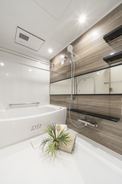 木目調パネルが上質な印象を与えるバスルームです。ワイドミラーも備えており、毎日のバスタイムが特別なひとときになります。