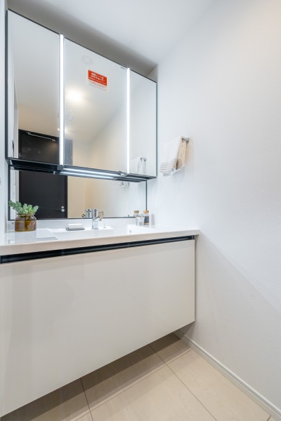 空間にすっきりと溶け込む洗面化粧台は三面鏡付き。豊富な収納があり、散らかりやすい小物類もたっぷりと収納いただけます。