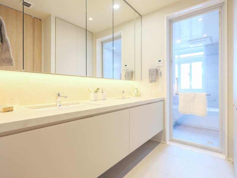 浴室の窓からの光も取り込む明るい洗面化粧室です。譲り合うことなくご使用いただけるダブルボールの洗面化粧台と床暖房を備え付けました。