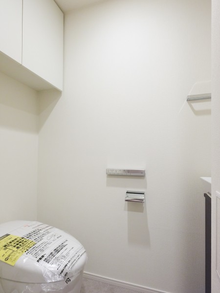 レストルームには、スマートな印象のタンクレストイレが備え付けられています。スティックリモコンや上部吊戸棚収納など、使い勝手の良さも備えた空間です。