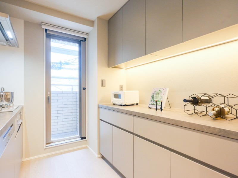 キッチン横手の扉はバルコニーへとつながっているため、採光性や換気も良好です。キッチン背面には収納豊富でカウンタースペースも広いカップボードがあります。
