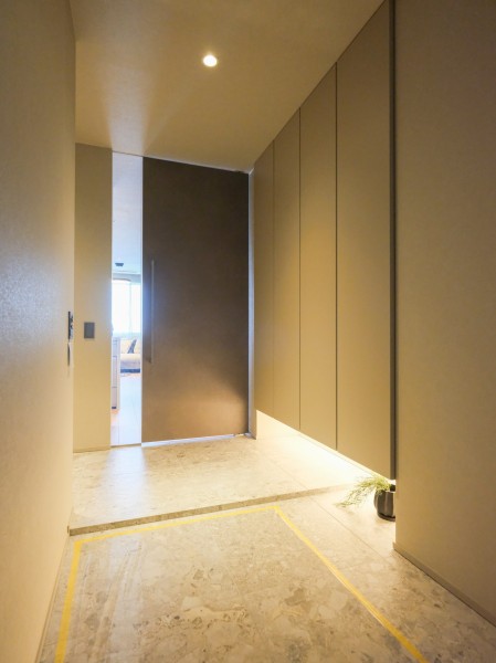 グレーでまとめられた空間を暖色のフットライトが照らし出し、シックで落ち着いた格調高い雰囲気に仕上がった玄関です。