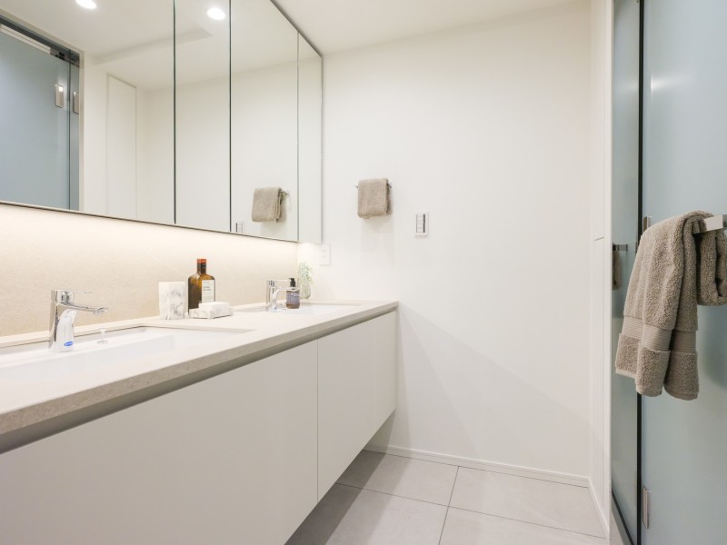 ホテルライクな２ボウル洗面化粧台を採用いたしました。お出かけ前の準備時間を快適にお過ごしいただける嬉しい仕様です。三面鏡裏や足元の収納棚があり、洗面室を広々とお使いいただけます。