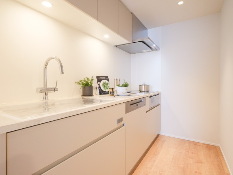 田中工藝製のシステムキッチンを造作いたしました。３口コンロやグリルがついており様々なお料理を作ることができます。淡い色調で統一しナチュラルな空間となっております。