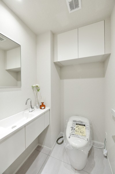 トイレは下階、上階に２か所設置しています。どちらにも鏡と手洗いカウンターを備え付けましたので、家族やゲストが気兼ねなく清潔に使用することができます。吊戸棚を設置していますので、小物類の収納にも便利です。