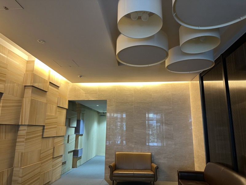 質感の異なる壁材を組み合わせたエントランスで、照明がその表情を柔らかく引き立てています。落ち着いたトーンでまとめられた、穏やかな雰囲気の空間です。