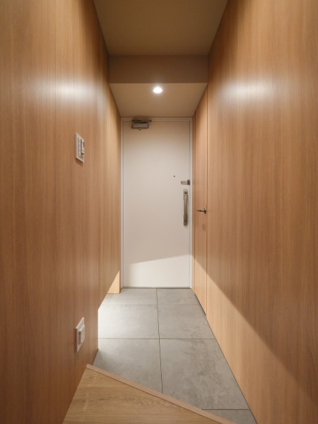 玄関の框を斜めにデザインすることで空間を広く見せる設計を施しました。​​住戸へ入室した瞬間に胸が躍る、お部屋の顔となる玄関。ウッド調の建具に包まれた心安らぐ住まいです。