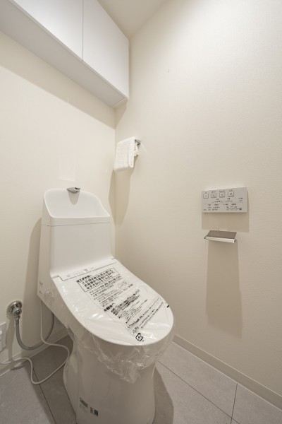 ウォシュレット一体型のトイレは、お掃除の手助けをしてくれる便利機能が搭載されています。上部には収納に便利な吊戸棚を備え付けました。