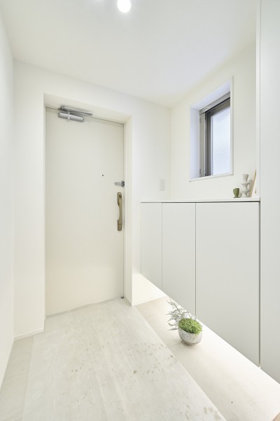 白を基調とした明るい玄関に、小窓からの自然光がやさしく差し込み、空間に心地よい明るさを添えています。足元が浮いたシューズボックスが軽やかな印象を生み、玄関全体をすっきりと見せてくれます。