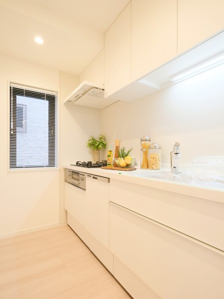 収納豊富な壁付けタイプのシステムキッチンには、家事時短に便利な食洗機も搭載しています。キッチン横にも窓があるため、明るいホワイト基調の空間に自然光が取り込めます。