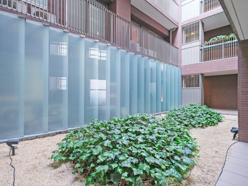 建物中央には植栽を配した中庭空間が設けられています。ガラスパネルと緑が調和し、共用部に開放感をもたらします。